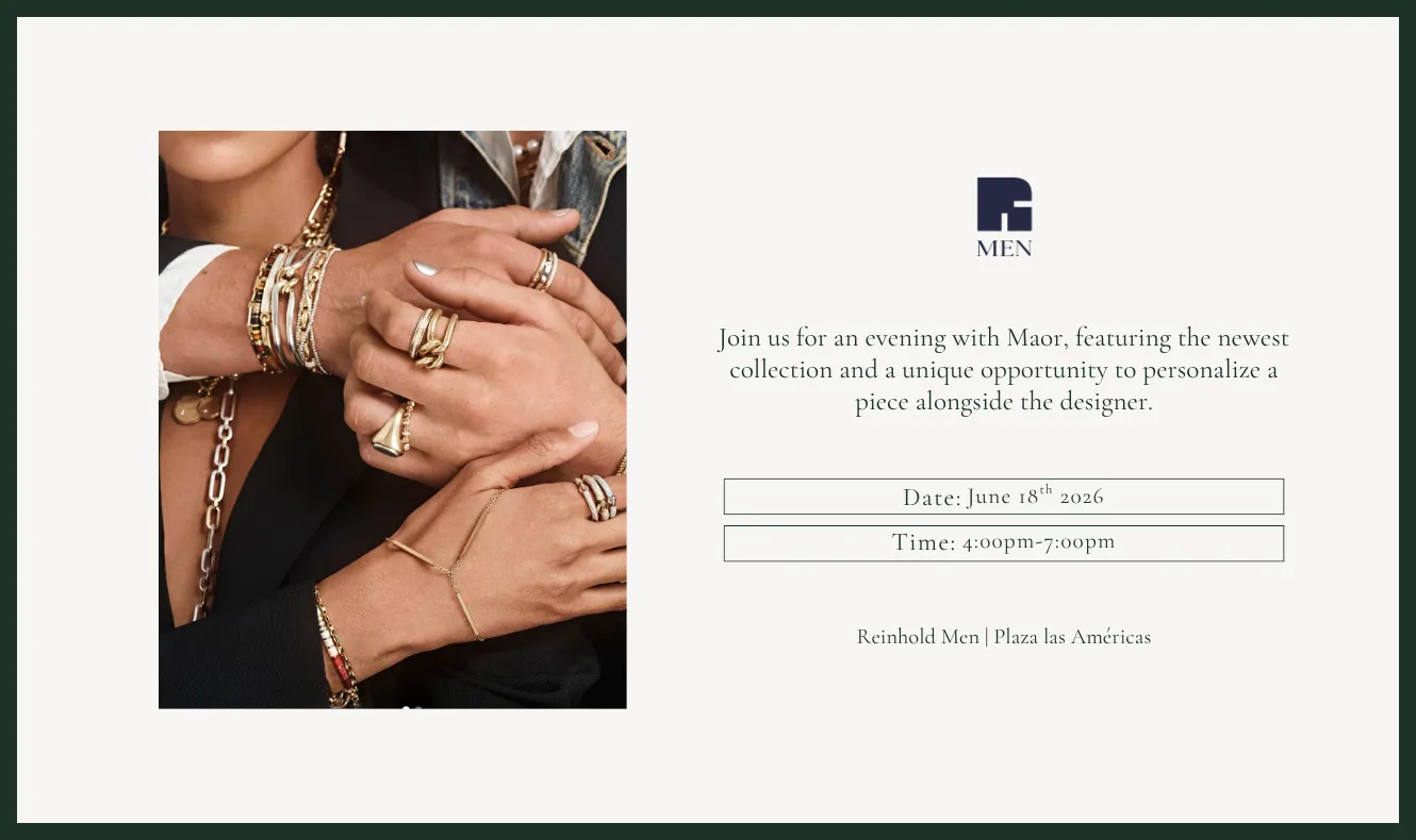 Close-up of layered jewelry worn on hands and wrists, including gold rings, bracelets, chains, and charms against a dark outfit.
